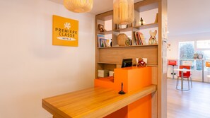 A reception desk with a wooden counter, a plush toy, and a sign reading "Premiere Classe Hotels". - Première Classe Nantes Sud - Rezé Aéroport (Reze)