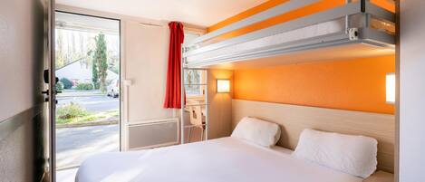 Una habitación de hotel con cama, escritorio y ventana con vistas a la calle.
