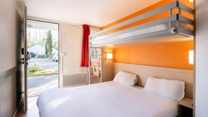 A hotel room with a bed, a desk, and a window with a view of the street. - Première Classe Nantes Sud - Rezé Aéroport (Reze)