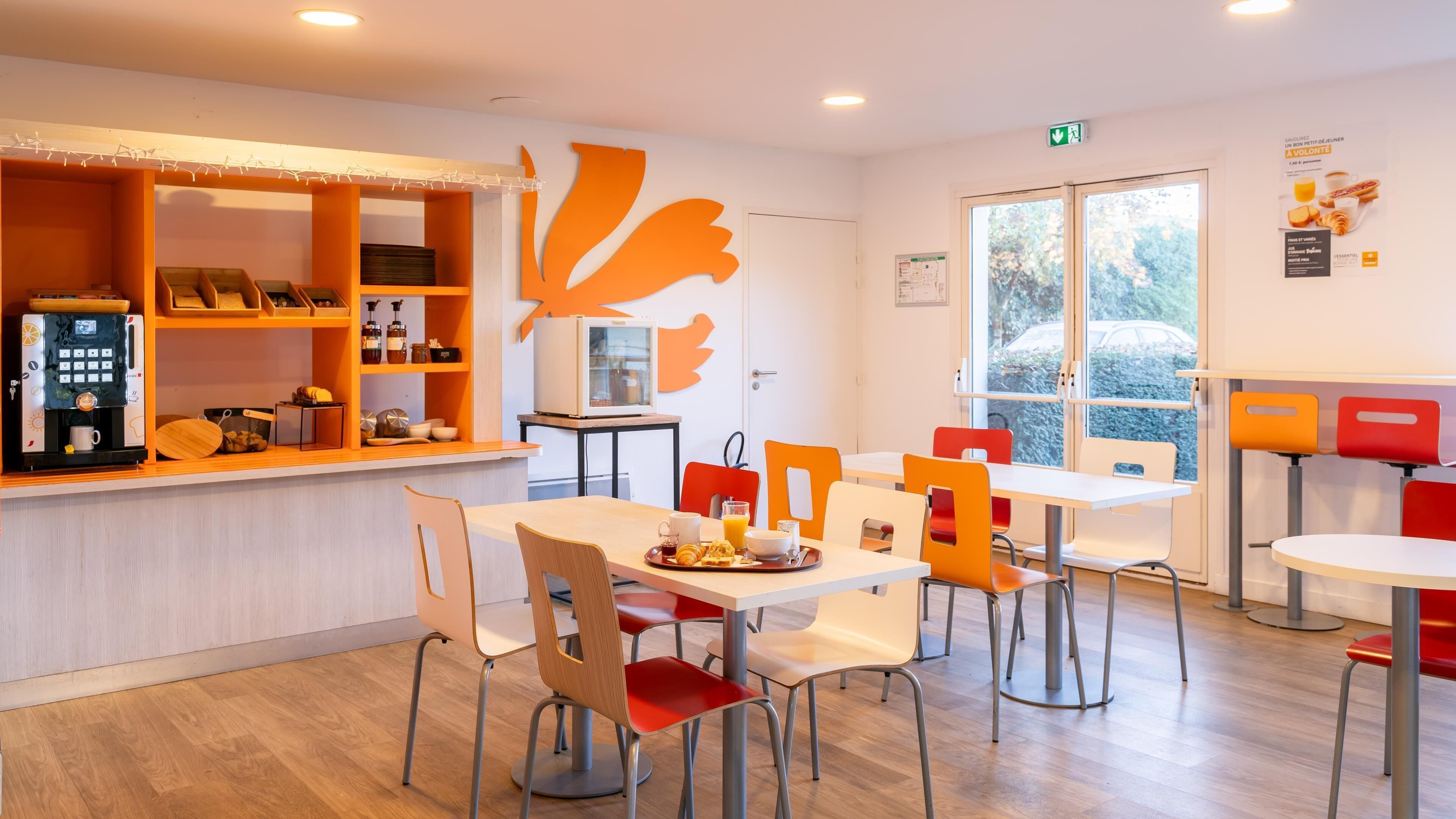 Un comedor moderno con cafetera, productos para el desayuno y un amplio ventanal con vistas al exterior.