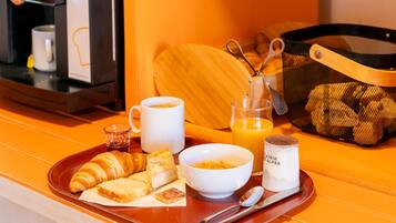 A breakfast tray with croissants, coffee, orange juice, and a bowl of cereal.