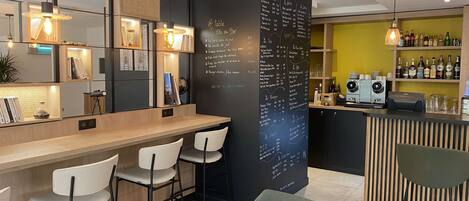 A modern bar area with a chalkboard menu, bar stools, and shelves with bottles.