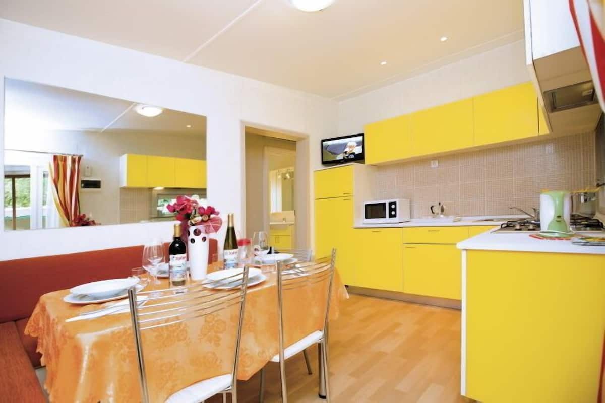 Une cuisine compacte avec des meubles de couleur jaune, un four à micro-ondes et un petit îlot central.