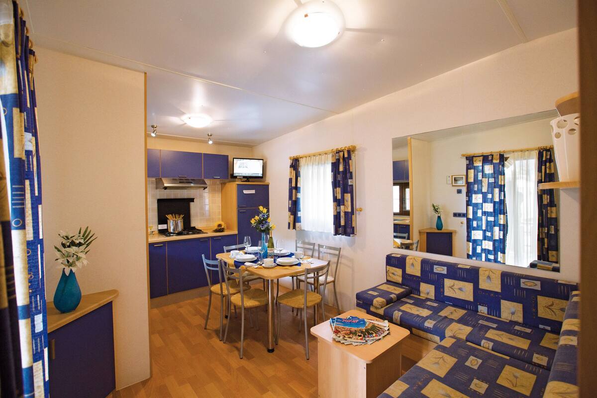 Un espace de vie compact comprenant un coin cuisine, un espace repas et un canapé.
