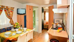 Une chambre d’hôtel compacte comprenant un coin repas, une kitchenette, un téléviseur et un petit lit.
