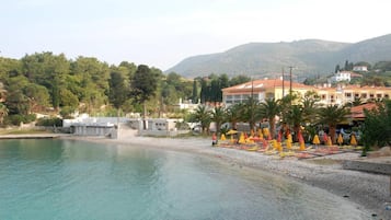 Una zona costera con una playa, un edificio de techo rojo y palmeras.