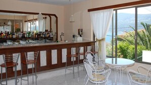 Uma área de bar com balcão, várias cadeiras e uma mesa.