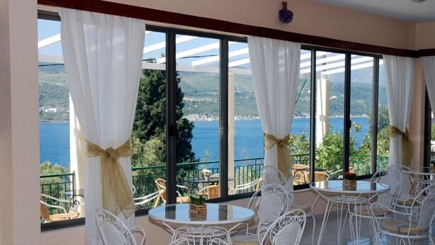 Terraço com mobiliário de vime branco e vista para o mar.