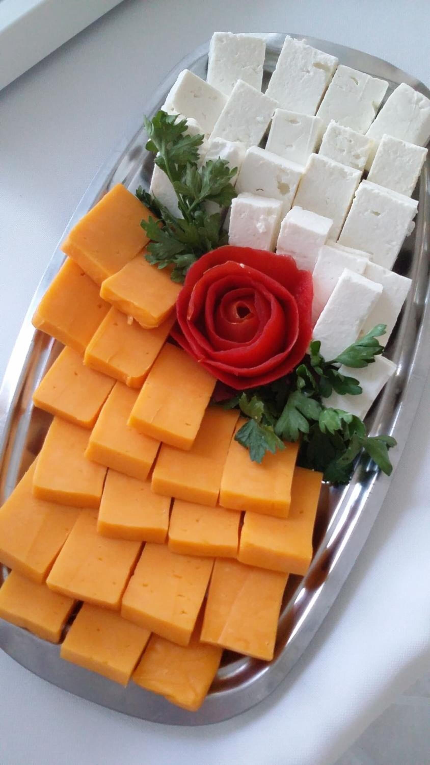 A platter with cheese and a decorative red rose.