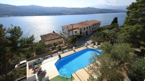 Uma vila com piscina, com vista para um lago e montanhas ao fundo.
