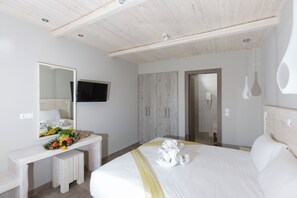 Una habitación de hotel con una cama grande, un tocador con espejo, una televisión y un armario.