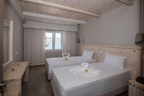 Une chambre d’hôtel avec deux lits, des têtes de lit en bois, un banc et une grande fenêtre avec des rideaux.