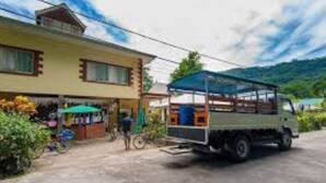 Un edificio con una pequeña tienda en la planta baja, una bicicleta aparcada y un camión con toldo.