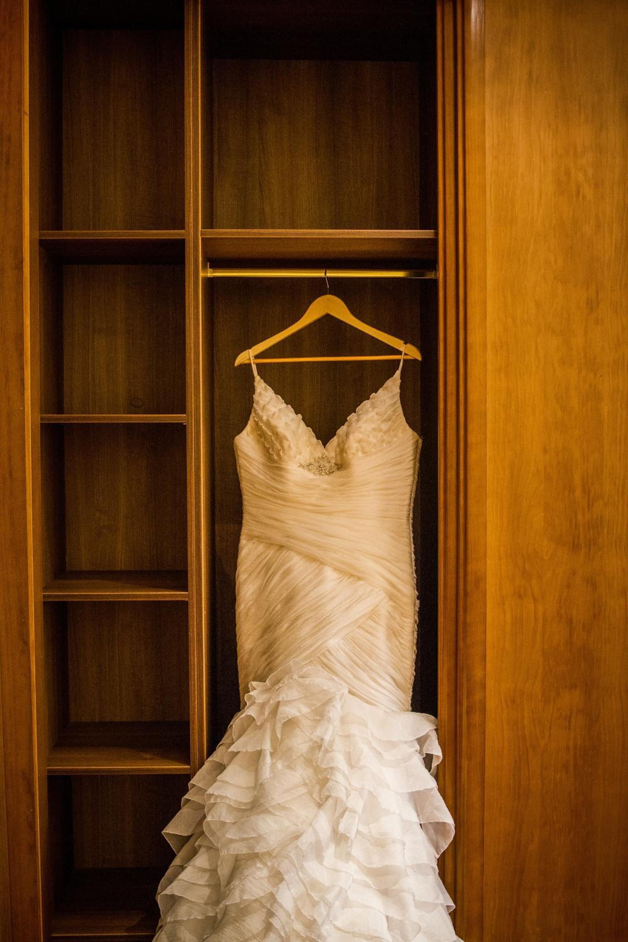 Un vestido de novia colgado en un armario de madera.