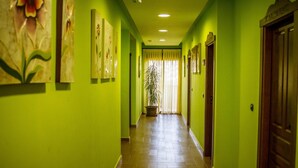 Un pasillo con paredes verdes, puertas de madera y una planta en maceta.