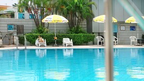 Una piscina con sillones blancos y sombrillas amarillas.