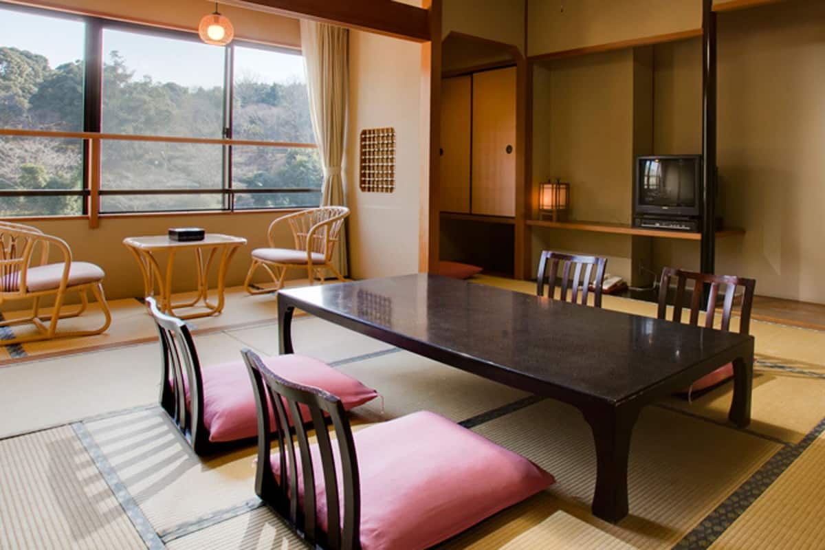 A traditional Japanese-style room with tatami flooring, a low table, and wooden chairs.