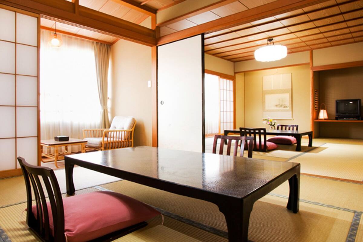 A traditional Japanese room with tatami flooring, a low table, chairs, and sliding doors.