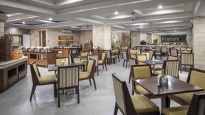 A spacious dining area with multiple tables and chairs, a buffet station, and a kitchen in the background. - Alia Cikini (Jakarta)