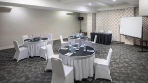 A conference room with round tables, white chairs, and a whiteboard. - Alia Cikini (Jakarta)