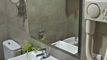 Un baño moderno con un espejo grande, un lavabo blanco, un inodoro y una zona de ducha.