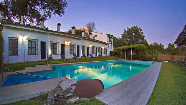 Una piscina con sillones de descanso y una casa al fondo.