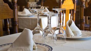 Una mesa de comedor con servilletas blancas, copas de cristal transparente y un plato con borde azul.