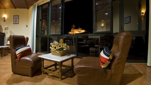 Una habitación con dos sillones de cuero, una mesita y un ventanal con vistas a un edificio iluminado en la noche.