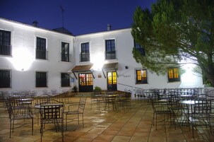 Un patio con mesas al aire libre y un edificio blanco con varias ventanas y puertas.