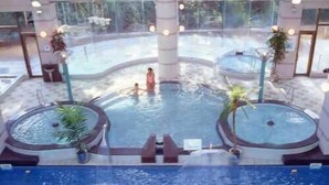 An indoor swimming pool with two hot tubs, a central pool area, and a view of the outside. - Kurhouse Shirahama (Shirahama)