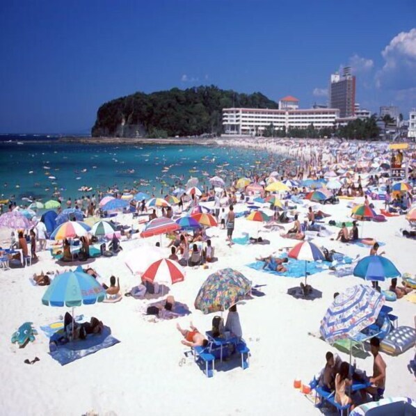 Una playa concurrida, con muchas sombrillas y gente tomando el sol.