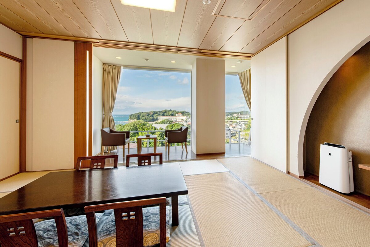 Una habitación con techo de madera, una mesa grande con sillas, televisor y vistas al paisaje.