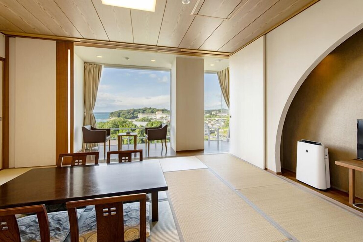 Una habitación con una mesa de comedor, sillas, un televisor y vistas a un paisaje.