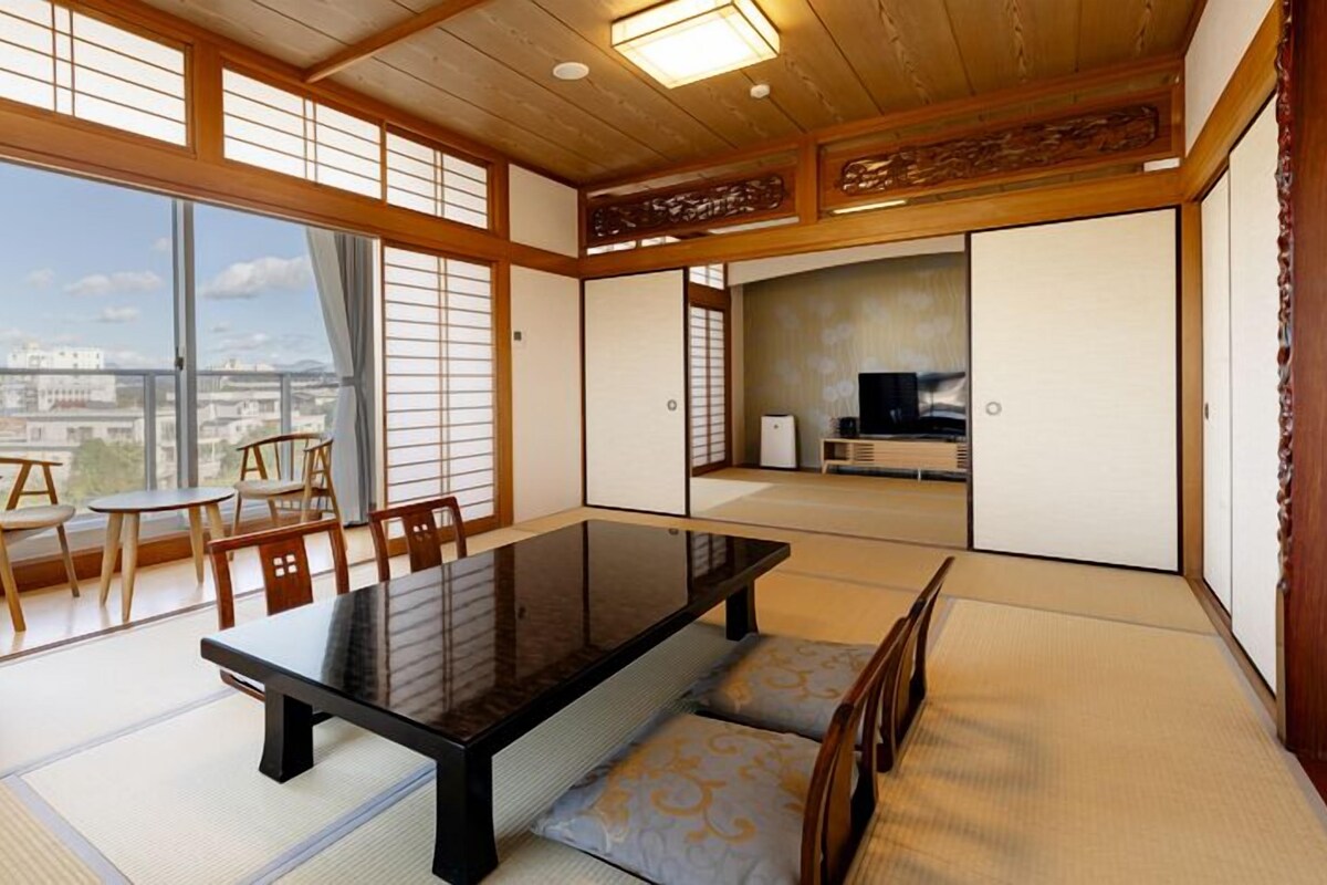 Una habitación tradicional japonesa con suelo de tatami, una mesa baja y puertas correderas.