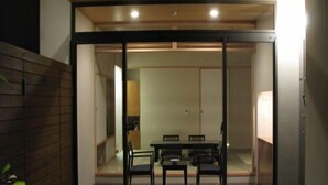 A modern interior with a dining area, sliding glass doors, and a small outdoor seating area. - Kurhouse Shirahama (Shirahama)