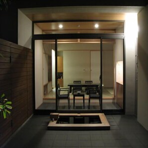 Un interior moderno con comedor, puertas de vidrio correderas y una pequeña zona de estar exterior.
