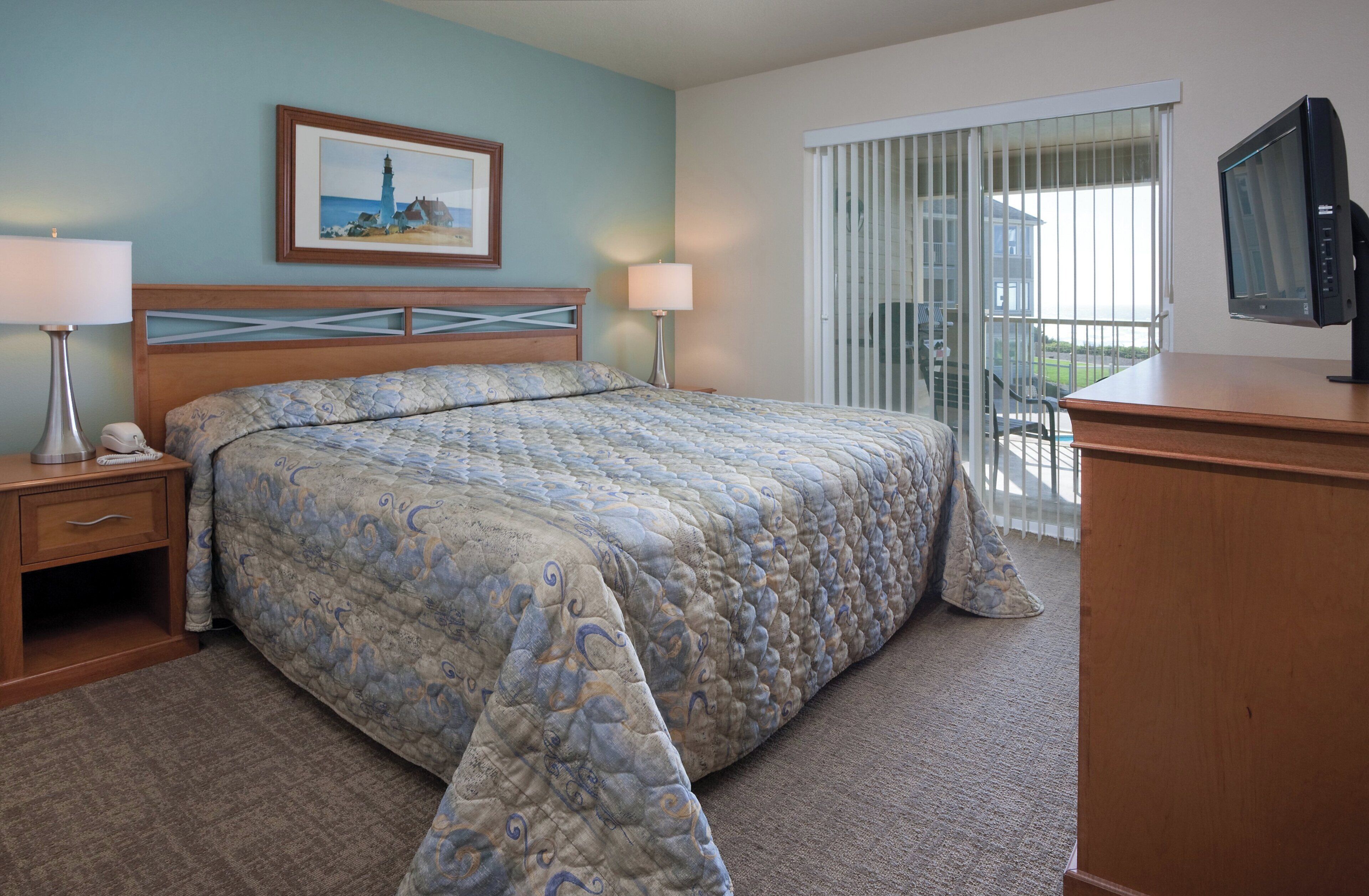 A hotel room with a large bed, two bedside tables, a television, and a window with a view of the outside.
