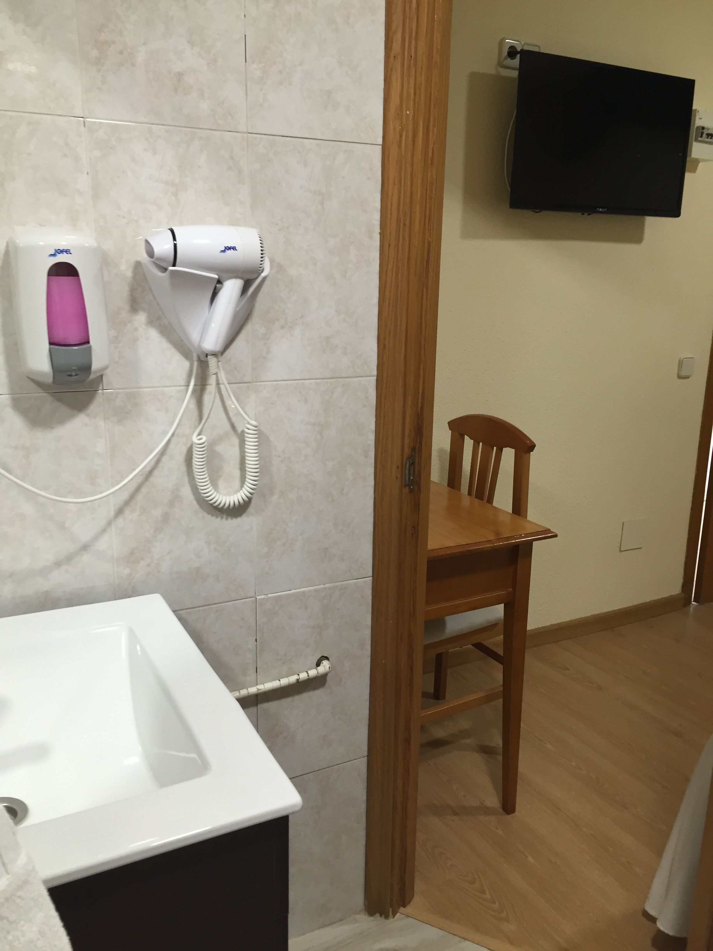 Un baño con lavamanos, secador de pelo y dispensador de jabón.