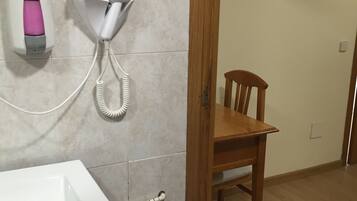 Un baño con lavamanos, secador de pelo y dispensador de jabón.