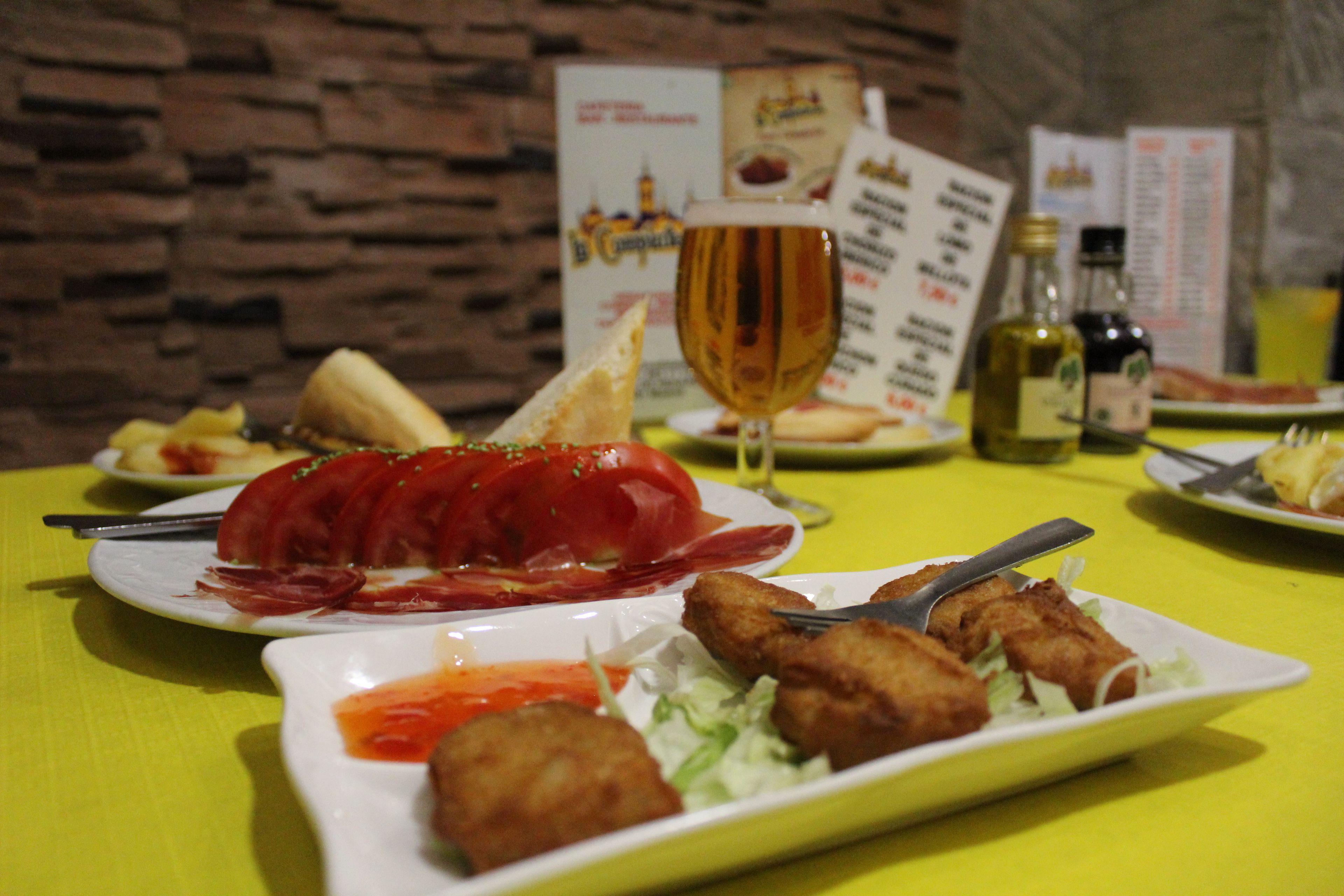 A table set with various dishes including a large platter of sliced meat, a glass of wine, and several plates of food.