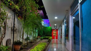 A hallway with a garden, a red sign, and a glass door on the right. - Hotel Boutique El Poblado (Neiva)