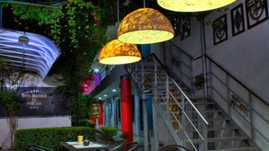 A hotel interior with a staircase, outdoor seating area, and hanging lamps. - Hotel Boutique El Poblado (Neiva)