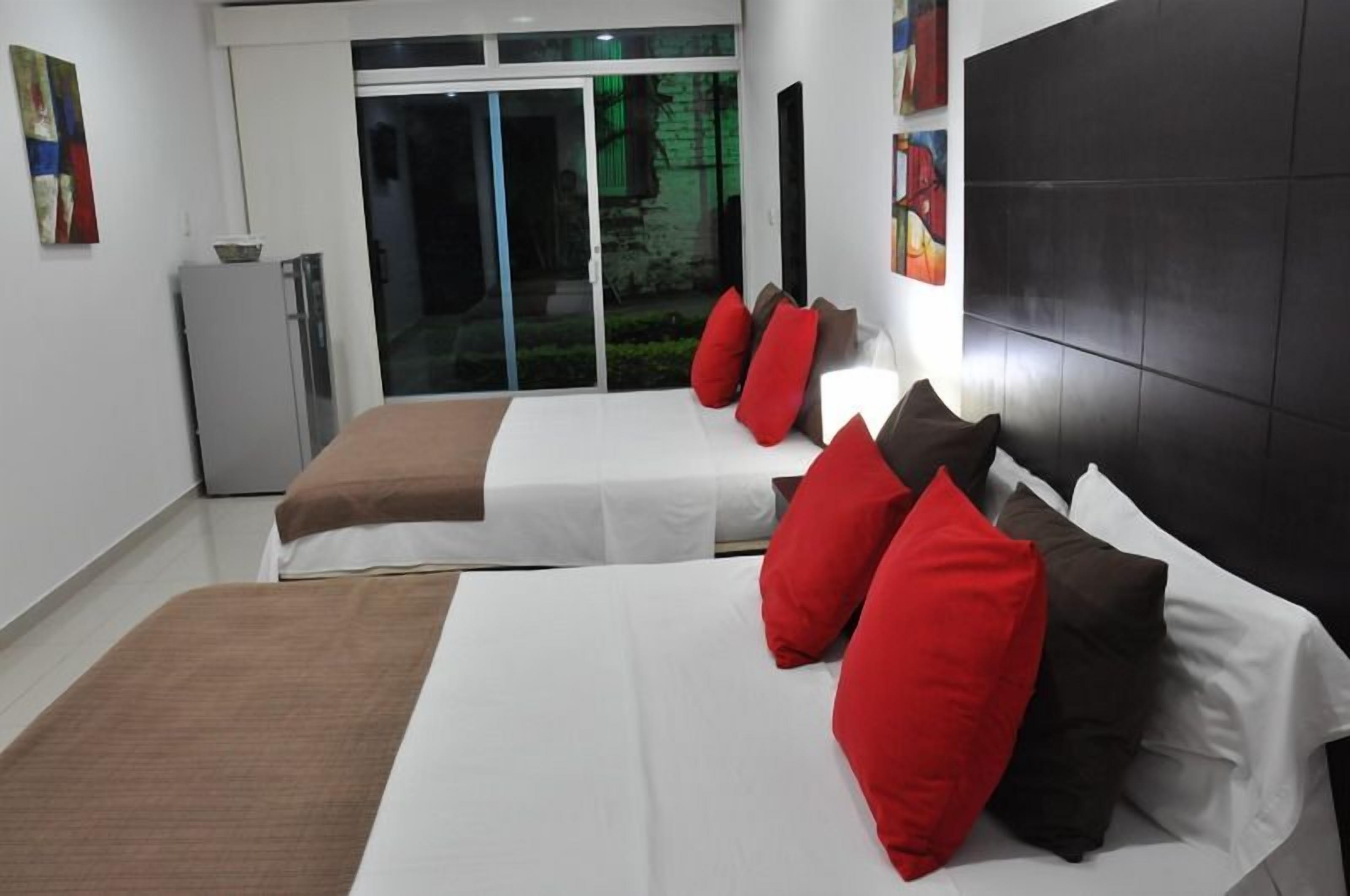 A hotel room with two beds, a sliding glass door to the outside, and a black headboard.