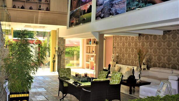 A spacious indoor area with a dining table and chairs, a sofa, and a bookshelf. - Hotel Boutique El Poblado (Neiva)