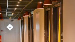Un pasillo de hotel con alfombra estampada, varias puertas y luces en el techo.