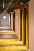 Un pasillo de hotel con alfombra estampada, varias puertas y luces en el techo.