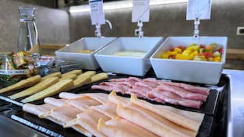 Un bufé con diversas opciones de comida, incluyendo queso, carnes y fruta.