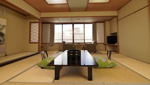 A traditional Japanese tatami room with a low table, tatami mats, sliding doors, and a television on a shelf. - Mori No Ryotei Mount Bandai (Inawashiro)