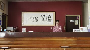A reception desk with a wooden counter, a framed calligraphy piece on the wall, and a door labeled "Office".