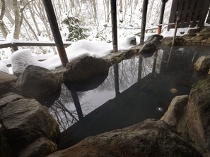 Eine ruhige Außenanlage mit einem kühlen Wasserspiel, umgeben von Steinen und einer Holzterrasse.